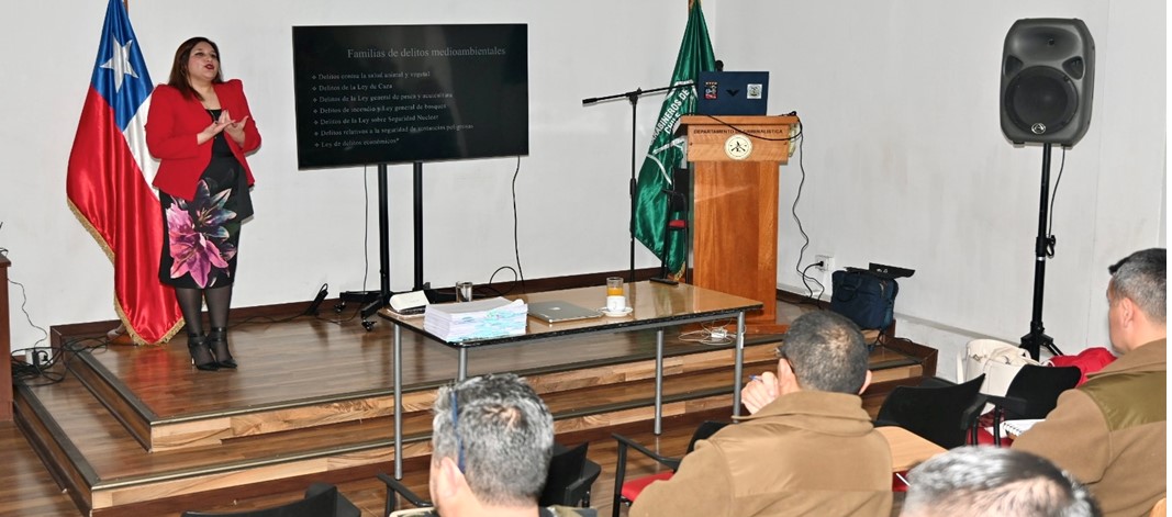 En la imagen se ve, de pie en el escenario, a la abogada de la Fiscalía Occidente dictando la capacitación a funcionarios de Carabineros.
